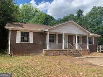 Charming brick ranch-style home featuring a cozy front porch and well-maintained landscaping at 13090 Brown Bridge Rd, Covington, GA 30016