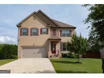 Charming two-story home with attached two-car garage and well-maintained front lawn and tasteful shutters at 8045 Coleson Xing, Locust Grove, GA 30248