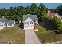 Charming two-story home with a well-manicured lawn and a two-car garage and mature trees in the background at 10074 Tara Glynn Dr, Hampton, GA 30228