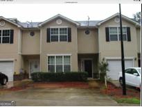 Inviting townhome featuring black shutters, white trim and a well-maintained front yard and garage at 2320 Coach Way, Jonesboro, GA 30236