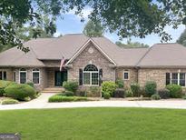 Charming single-story home with a stone and brick facade, a well-manicured lawn, and lush landscaping at 232 Darwish Dr, Mcdonough, GA 30252