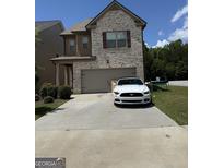 Two-story home with light brick, a two-car garage, and a concrete driveway at 11909 Lovejoy Crossing Blvd, Hampton, GA 30228