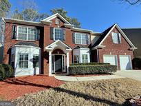 Charming two-story brick home with a manicured lawn, two-car garage, and beautiful bay windows at 3065 Moser Way, Marietta, GA 30060