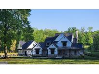 Stunning two-story modern farmhouse with a stone chimney, black metal roof and mature trees at 155 Green Meadow Ln, Fayetteville, GA 30215