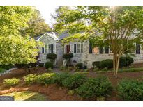 Charming brick home featuring a beautifully landscaped front yard with mature trees and lush greenery at 17 Hampton Way, Carrollton, GA 30116