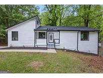 Charming renovated home featuring white siding, black trim, and a freshly landscaped front yard at 9438 Cedar Creek Pl, Douglasville, GA 30135