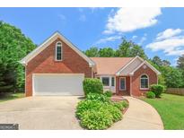 Charming brick home featuring an attached garage, manicured landscaping, and a curved walkway leading to the entrance at 3533 Saddlebrook Dr, Loganville, GA 30052