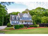 Charming two-story traditional home with blue shutters, a welcoming front porch, and professionally landscaped yard at 855 Hood Rd, Fayetteville, GA 30214
