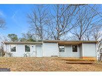 Exterior view of a one-story home with light blue siding and bare trees against a blue sky at 8005 Big Rock Dr, Douglasville, GA 30134