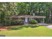 Charming brick home features lush green lawn, mature trees, and a convenient carport at 1749 Creat Se Trl, Smyrna, GA 30080