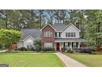 Charming two-story home with a brick facade, a welcoming front porch, and manicured landscaping at 908 Huntington Pl, Peachtree City, GA 30269