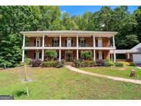 Stunning two-story brick home with double balconies, columns, a well-manicured lawn, and a walkway at 871 Rocky Creek Rd, Hampton, GA 30228
