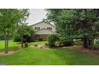 Charming two-story home featuring a lush, green lawn and mature trees in a serene, residential setting at 7369 Aubrey Dr, Riverdale, GA 30296