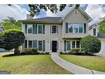 Charming two-story home with a landscaped yard, black shutters and a curved walkway leading to the front door at 1311 Bustling Sw Ln, Marietta, GA 30064