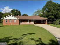 Traditional brick home with a well-manicured lawn and a long driveway under a blue sky at 18 North Ave, Hampton, GA 30228