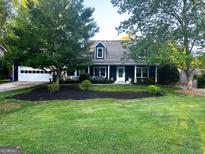 Charming blue two-story home with a well-manicured lawn and beautiful landscaping, inviting front porch at 209 Hearthstone Reach, Peachtree City, GA 30269