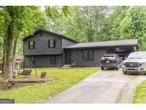Charming two-story home with dark siding, a metal roof carport, and a well-maintained front lawn at 870 The Cir, Lawrenceville, GA 30043