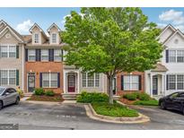 Charming townhome with brick accents, complemented by lush landscaping and a mature shade tree at 1363 Penhurst Dr, Lawrenceville, GA 30043
