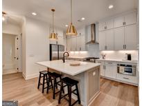 Bright white kitchen features a large island with seating and modern stainless steel appliances and fixtures at 1006 Fendley St, Woodstock, GA 30188