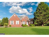 Charming brick home with well-manicured lawn and mature trees on a sunny day at 161 Pleasant Grove Rd, Mcdonough, GA 30252