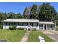 Modest one-story home with a traditional design, lawn, and mailbox, shaded by mature trees at 1028 Dixie Dr, Jonesboro, GA 30236