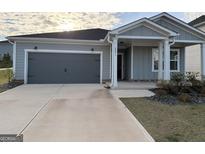 Charming home with gray siding, a two-car garage, and a well-maintained front yard at 2051 Blue Sky Ave, Covington, GA 30016