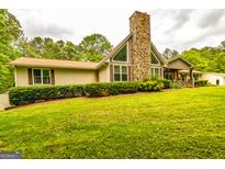 Charming home with a stone chimney, complemented by a lush green lawn and mature trees at 130 Brooklet Way, Brooks, GA 30205