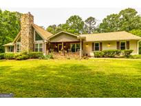 Charming home featuring a stone chimney, inviting front porch, and well-maintained landscaping at 130 Brooklet Way, Brooks, GA 30205