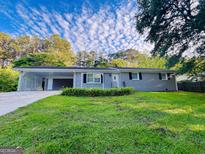 Charming single-story home with a well-maintained lawn, carport, and grey brick exterior at 229 Timberland Trl, Riverdale, GA 30274