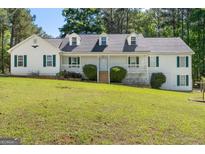 Charming two-story home featuring a covered porch and a well-manicured front yard and mature trees at 3499 S Ola Rd, Locust Grove, GA 30248
