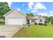 Charming one-story home with vinyl siding, attached garage, and a well-maintained lawn and landscaping at 1704 New Hope Rd, Locust Grove, GA 30248
