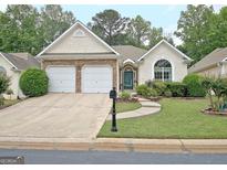 Charming single-story home with stone accents, a two-car garage and well-maintained landscaping at 323 Newfield Way, Peachtree City, GA 30269