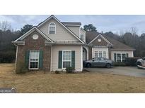 Charming home showcasing a combination of tan siding and brick facade, complemented by dark green shutters and a well-manicured lawn at 127 Autumn Run Pl, Villa Rica, GA 30180