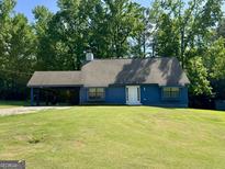 Charming blue home with a well-manicured lawn and a convenient covered carport at 105 Harris Ct, Stockbridge, GA 30281