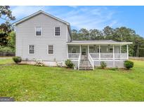 Charming gray home with a welcoming white porch, complemented by a lush green lawn and mature trees at 1125 Babbs Mill Rd, Hampton, GA 30228
