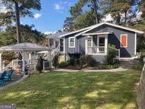 Charming blue-gray home with a well-manicured lawn, gazebo, and mature trees at 22 Waters Bridge Cir, Covington, GA 30014