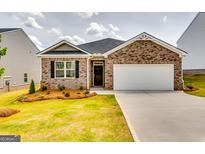 Charming brick home with a manicured lawn and a two-car garage under a cloudy sky at 616 Whitman Ln # 30, Stockbridge, GA 30281