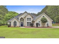 Stunning two-story home with a well-manicured lawn, decorative shrubbery, and a blue front door at 391 Massengale Rd, Brooks, GA 30205
