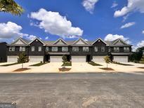 New row of brick townhomes featuring attached garages and manicured landscaping at 240 Epping Dr, Stockbridge, GA 30281