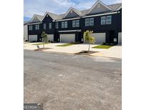 Row of new, modern townhomes with attached garages in a neat community with well-maintained landscaping and a street view at 256 Epping Drive, Stockbridge, GA 30281