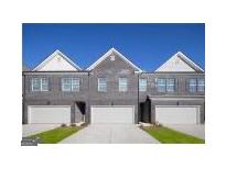 Charming brick townhomes featuring individual garages and manicured lawns under a clear blue sky at 256 Epping Drive, Stockbridge, GA 30281