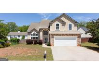 Charming two-story home with a stone veneer and a well-manicured front yard under a clear blue sky at 2805 Topaz Rd, Riverdale, GA 30296