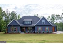 Charming single-story home boasts a well-manicured lawn, stone accents, and a welcoming front porch, perfect for relaxing at 227 Wet Wood Ct, Fairburn, GA 30213