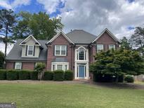 Charming brick home with a well-manicured lawn, blue front door, and classic architectural details at 840 Yosemite Dr, Suwanee, GA 30024