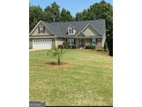 Charming home featuring a two car garage, stone accents, and a well maintained lawn at 565 Miles Ct, Locust Grove, GA 30248
