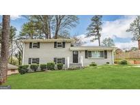 Charming two-story home with painted brick, black shutters, green lawn, and mature trees at 4049 Brookcrest Cir, Decatur, GA 30032