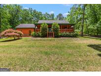 Charming home exterior with a cozy porch, lush greenery, and well-manicured lawn at 3313 Henson Ln, Stockbridge, GA 30281