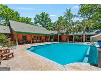 A beautiful in-ground pool with patio, pool-side bar, and wooden home exterior surrounded by mature trees at 3313 Henson Ln, Stockbridge, GA 30281