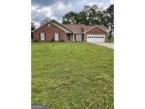 Charming single-story brick home featuring an attached two-car garage and a well-maintained lawn at 201 Summerford Pl, Stockbridge, GA 30281