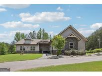 Beautiful exterior elevation featuring stone accents, gray siding, a well-manicured lawn, and a circular driveway at 411 Johnson Rd, Locust Grove, GA 30248